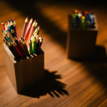 Lápices de colores en dos botes de madera sobre una mesa