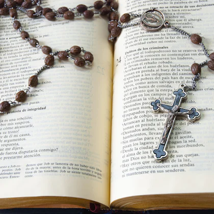 Rosario de madera con una cruz, encima de una biblia abierta