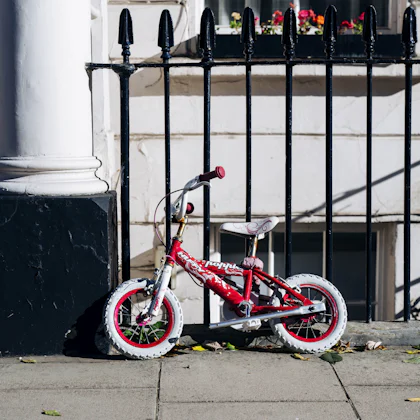 Bicicleta infantil roja aparcada junto a una verja