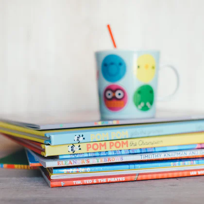 Pila de libros infantiles con una taza encima
