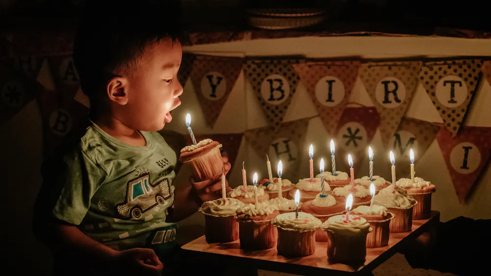 Un niño a punto de soplar las velas de unas magdalenas de cumpleaños