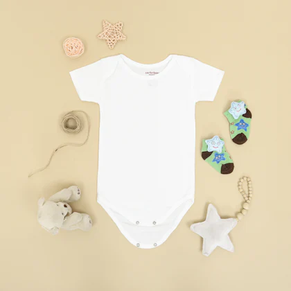 Body blanco de bebé rodeado de calcetines y un peluche, sobre fondo beige
