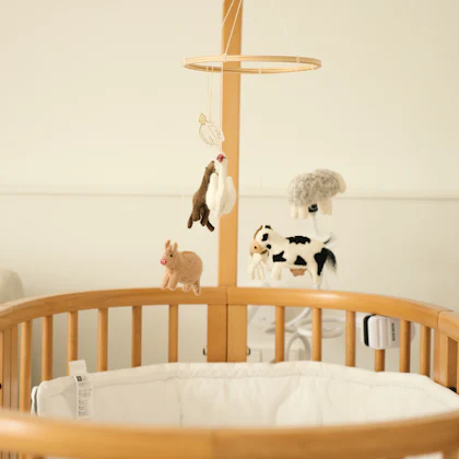 Cuna de madera con un móvil de animales de fieltro colgado encima