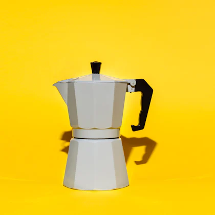 Cafetera italiana de aluminio sobre un fondo amarillo